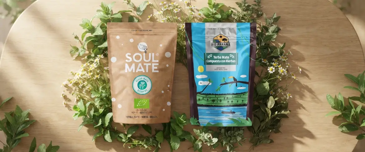 Embalagens tipo «doypack» de erva-mate com hortelã-pimenta e ervas, numa composição natural sobre um fundo de madeira.